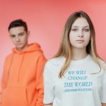 Young people in vibrant outfits promoting social change with empowering text on a t-shirt.